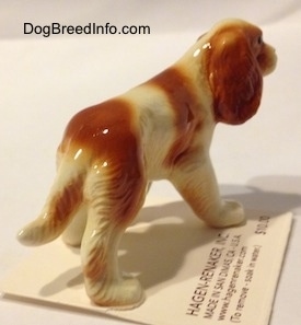 The back right side of a red and white Cavalier King Charles Spaniel figurine. The figurine has detailed paws.