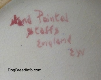 There are words on the underside of a porcelain pitcher. The words read - Hand Painted Staffs England EW.