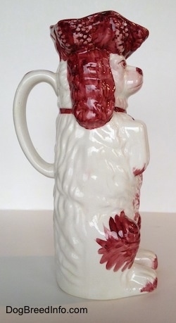 The right side of a white and red Cavalier King Charles Spaniel porcelain water pitcher. The pitcher has red on its paws.