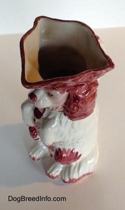 Top down view of the spout of a white and red Cavalier King Charles Spaniel porcelian water pitcher.