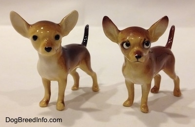 Two different Chihuahua ceramic figurines. Both figurines have arched up tails.