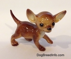 The right side of a brown with tan ceramic Chihuahua dog figurine. The dog has black circles for eyes.