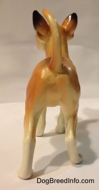 The back of a porcelain tan with white Chihuahua figurine. The figurine has white paws.