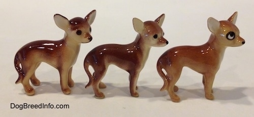 The right side of three different ceramic Chihuahua figurines. The back two figurines have black circles for eyes and a nose.