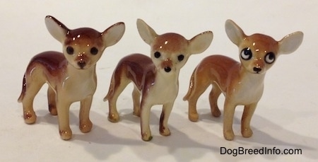Three Chihuahua ceramic figurines that are the same but painted differently. They have round heads, black noses and large ears that are set wide apart and stick out to the sides.
