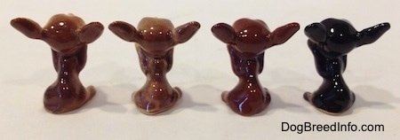 The back of four different Chihuahua figurines in a begging position. The figurines do not have tails.