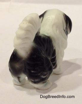 The back right side of a black and white bone china Japanese Chin dog figurine.