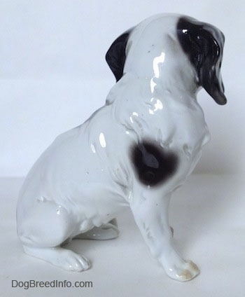 The right side of a white with black Japanese Chin dog figurine. It only has one black spot on its right side.