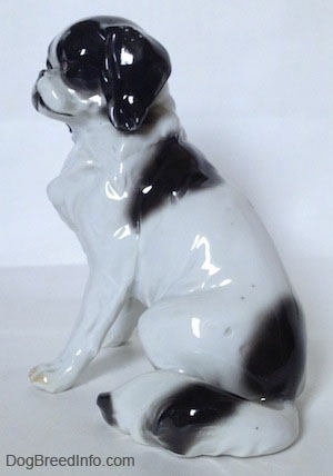 The left side of a white with black vintage Goebel Japanese Chin dog figurine. The figurine is glossy.