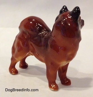 The front left side of a Chow Chow figurine that is in a standing pose. The back of the figurine ears are black.