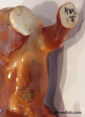 Close up - A Royal Doultan logo is stamped on the bottom of a Chow Chow figurine. On the lef is the letter/number combination - K05J