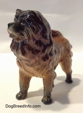 The front left side of a brown with black Chow Chow figurine. The figurine has very few details in its face. The dog has a big head, thick body and a black nose.
