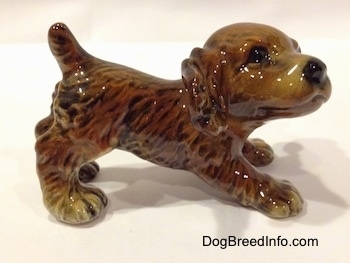 The right side of a brown and tan Cocker Spaniel puppy figurine. The figurine has very defined ears.