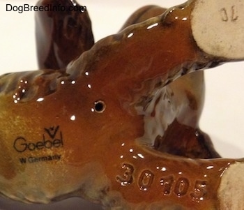 Close up - The underside of a brown and tan Cocker Spaniel puppy figurine. The logo for Goerbel W. Germany and a series of numbers are displayed.