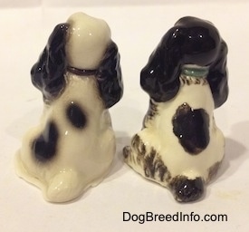 The back side of two different ceramic Cocker Spaniel figurines. They both have long black ears that hang down to the sides of their heads.