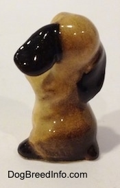 The back of a tan with brown ceramic Cocker Spaniel puppy figurine. The painting gradient on the figurine