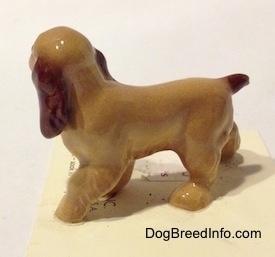 The left side of a tan with brown ceramic Cocker Spaniel figurine. It has a brown tail.