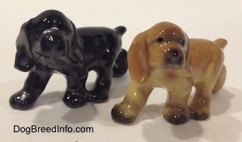 The front left side of two different ceramic Cocker Spaniel puppy figurines. They have short tails.