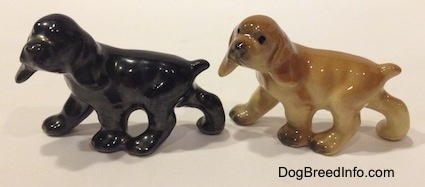 The left side of two different ceramic Cocker Spaniel puppy figurines. The right most figurine has more details than the left one.