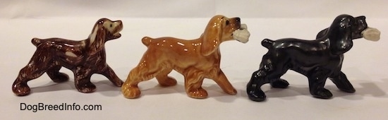 The right side of three different Cocker Spaniel figurines. The figurine furthest to the left has visible wear and tear.