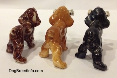The back right side of three different Cocker Spaniel figurines. The figurines has short tails