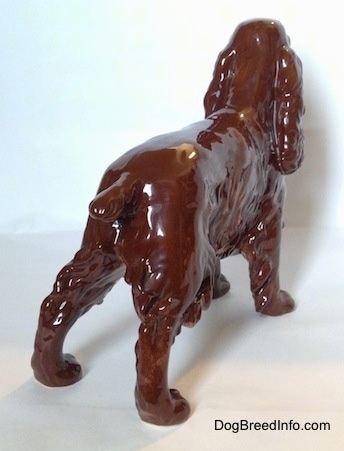 The back right side of a brown with black Cocker Spaniel dog porcelain figurine. It has a short tail.