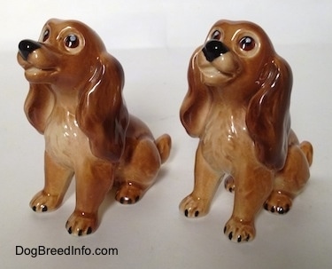 The front left side of two brown and tan Cocker Spaniel puppy figurines. The figurines look like they have smiles on them.
