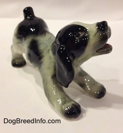 The front right side of a white and black Cocker Spaniel puppy figurine. It has lightly detailed eyes.