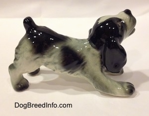 The right side of a white and black Cocker Spaniel puppy figurine. It has lightly detailed hair brushings.