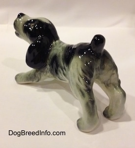 The back left side of a white and black Cocker Spaniel puppy figurine. It has lightly detailed eyes.