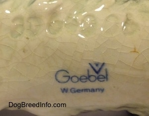 The underside of a white and black Cocker Spaniel puppy figurine the logo of Goebel W. Germany is displayed.
