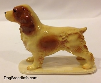 The left side of a tan with brown ceramic Cocker Spaniel figurine. The back end of the figurine has fine hair details.
