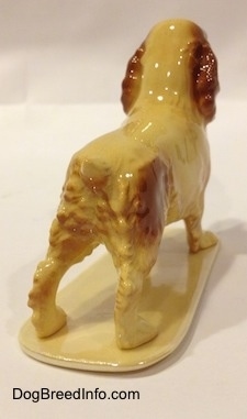 The back right side of a tan with brown ceramic Cocker Spaniel figurine.