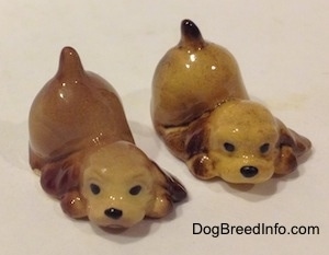 Two brown and tan ceramic Cocker Spaniel puppy figurines that are play bowing.