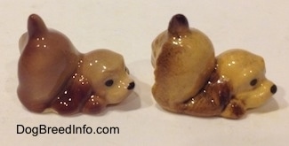The right side of two brown and tan ceramic Cocker Spaniel puppy figurines that are play bowing. They are very glossy.