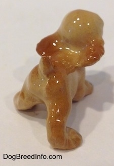 The back right side of a tan ceramic Cocker Spaniel puppy running figurine. The figurine is painted finely.