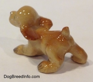 The front left side of a tan ceramic Cocker Spaniel puppy running figurine.