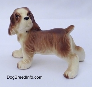 The left side of a brown and white ceramic Cocker Spaniel puppy figurine. It has great hair details.