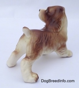 The back right side of a brown and white ceramic Cocker Spaniel puppy figurine. The figurine has fine hair details.