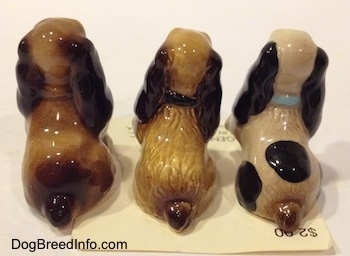 The back side of three different Cocker Spaniel puppy figurines. The figurines have varing degrees of detail.