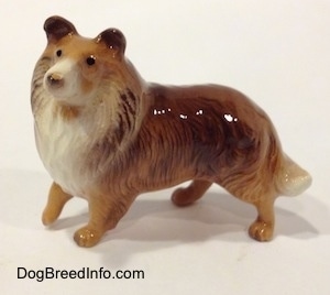 The left side of a brown with white Collie dog figurine. The figurine has small black circles for eyes.