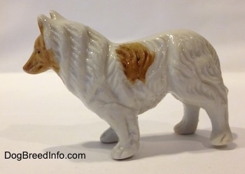 The left side of a bone china figurine that is a white with tan Rough Collie. The figurine has fine paw details.
