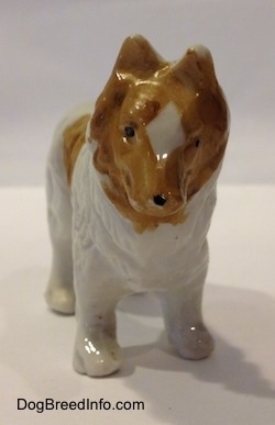 A bone chine white with tan Rough Collie figurine. The figurine has a black dot for a nose.