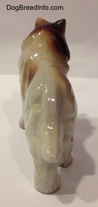 The back of a brown and white porcelain Rough Collie figurine. The figurine has a long tail.