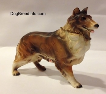 The front right side of a brown, black and white ceramic Rough Collie figurine. The figurine has a detailed face.