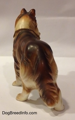The back of a ceramic figurine that is a brown, black and white ceramic Rough Collie figurine. The figurine has a long tail.