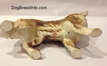 The underside of a ceramic Rough Collie figurine. There is a sticker across the bottom of the figurine.