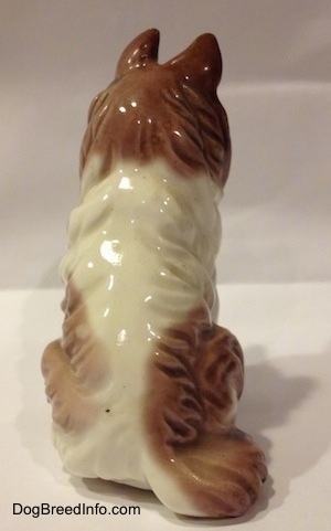 The back of a porcelain figurine that is a brown and white Rough Collie. The tail of the figurine is hard to differentiate from its body.