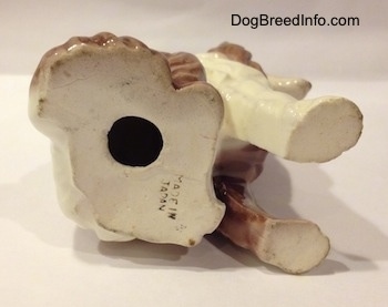 The underside of a brown and white porcelain Rough Collie figurine that has a hole in the bottom.