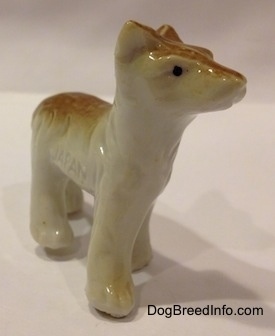 The front right side of a tan and white bone china Coyote figurine. The figurine paws has no details.